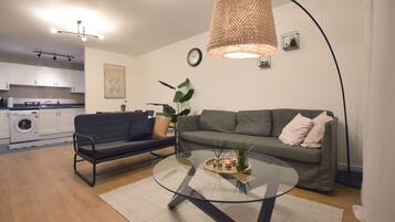 A modern living room with a glass coffee table, a sofa, and a hanging light fixture.