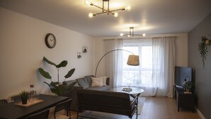 Ein modernes Wohnzimmer mit Essbereich, einer Couch, einem Couchtisch und einer TV-Kommode.