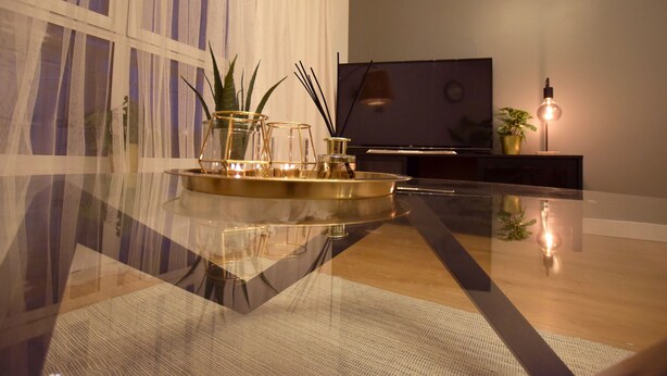 Ein modernes Wohnzimmer mit einem Glastisch, einem Flachbildfernseher und Zimmerpflanzen.