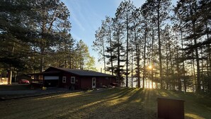 A cabin with a garage, surrounded by tall trees and a clear sky. - Top Boating, fishing, swimming-summer AND winter destination in Wisconsin! (Hayward)