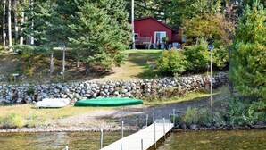 A wooden dock extending into a calm lake, surrounded by a stone wall and lush greenery. - Top Boating, fishing, swimming-summer AND winter destination in Wisconsin! (Hayward)
