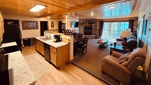 A spacious kitchen with wooden cabinets, a central island, and a stone fireplace. - Top Boating, fishing, swimming-summer AND winter destination in Wisconsin! (Hayward)