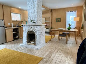 Une cuisine moderne avec une cheminée en pierre, des armoires en bois et un coin repas comprenant une table et des chaises.