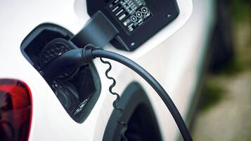 Un primo piano di un cavo di ricarica per veicoli elettrici collegato a una stazione di ricarica.