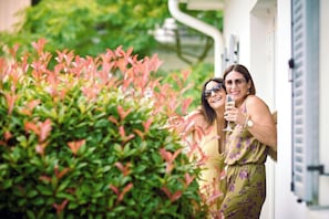 Two individuals standing in front of a building with a lush green hedge. - Riverside, private boutique apartments with garden (Mosonmagyaróvár)