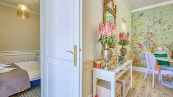 Un dormitorio con cama, armario blanco, tocador con espejo y un mural floral en la pared.