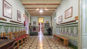 A hallway with patterned floor tiles, wooden benches, and framed pictures on the walls.