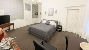 A neatly arranged bedroom with a bed, bedside tables, a TV, and a dining area with a table and chairs. - Cozy, and private apartment near Lake Shelbyville (Shelbyville)