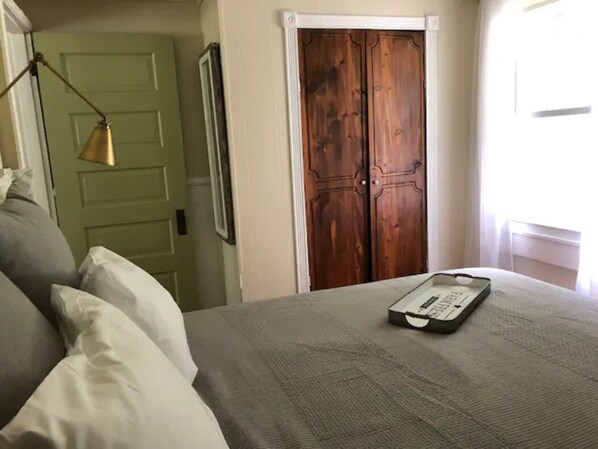 A bedroom with a bed, pillows, a tray, a wooden wardrobe, and a lamp.