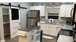 A modern kitchen with white cabinets, a stainless steel refrigerator, a microwave, and a built-in oven. - All New Deland Den 4BR, pool, blocks fr Stetson & Downtown (DeLand)