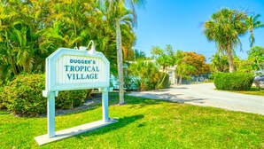 A sign for Dugger's Tropical Village with a pathway leading to a building. - Brand New to the rental market ! (Sanibel)