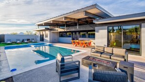 A modern house with a swimming pool, outdoor seating, and a covered patio area.