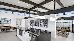 A modern kitchen with a central island, white cabinetry, and a large window overlooking a scenic view.
