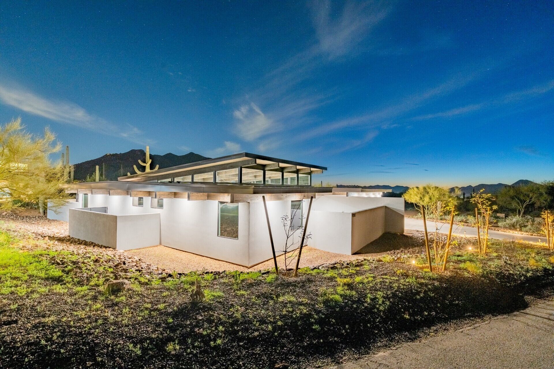 A modern house with a flat roof, large windows, and a desert landscape in the background.