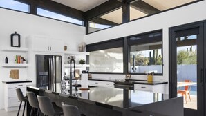 A modern kitchen with a large island, bar stools, and a view of the outdoors.