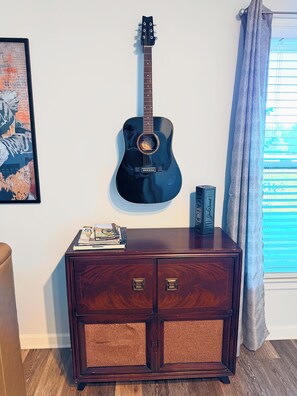 Un mueble de madera oscura con dos puertas y una guitarra colgada en la pared superior.
