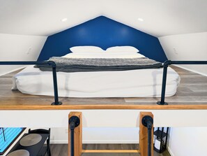 A modern bedroom with a bed, a blue accent wall, and a wooden floor. - Franklin tiny home with a fully fenced yard and deck, just 9 minutes to downtown (Franklin)
