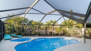 Une piscine couverte avec deux piscines plus petites, entourée d’une clôture en métal et de palmiers.