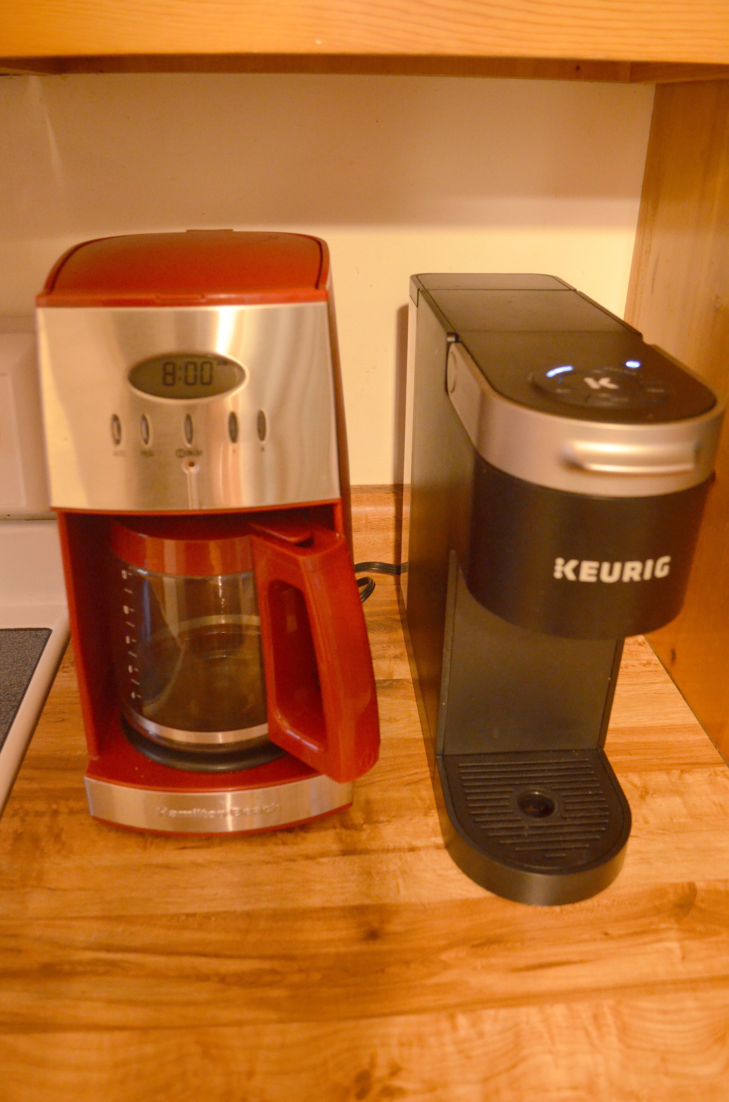 Eine rote und schwarze Keurig-Kaffeemaschine auf einer Holztischplatte.