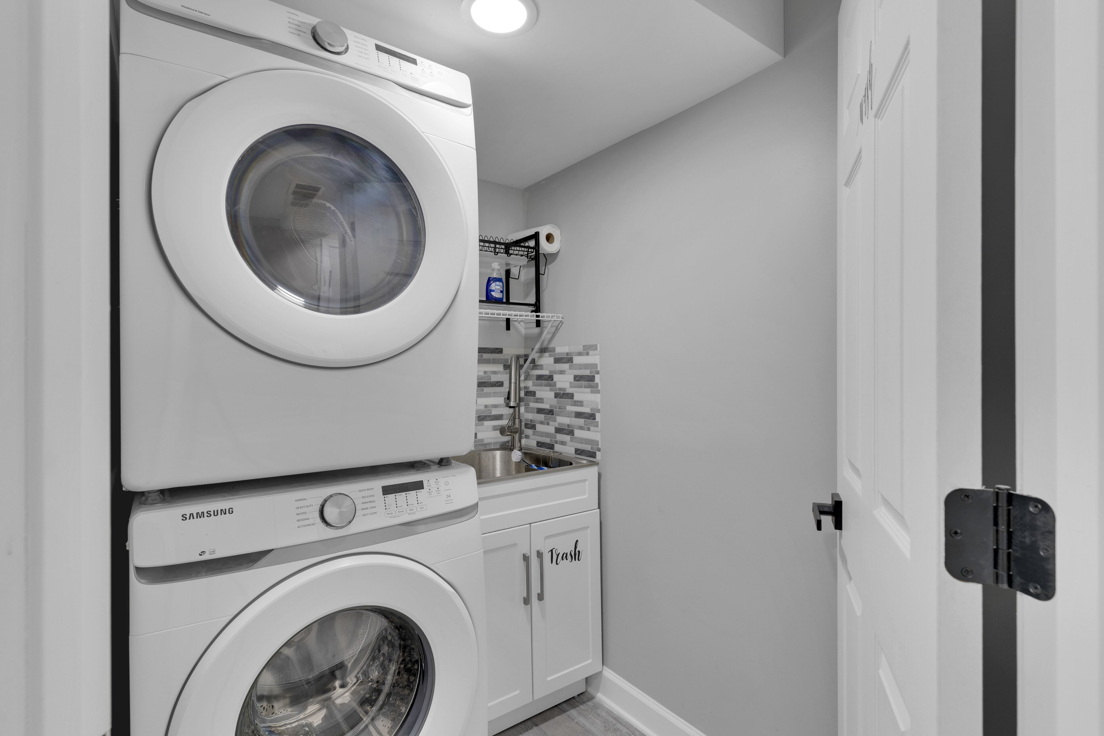 A compact laundry area with stacked washing machines and a small sink.