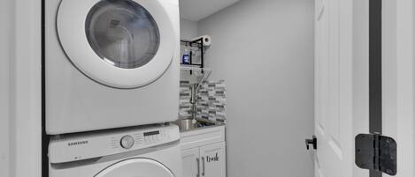 A compact laundry area with stacked washing machines and a small sink.