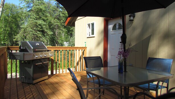 An outdoor deck with a grill, a table with chairs, and an umbrella. - Peaceful Talkeetna Getaway 4 (Talkeetna)