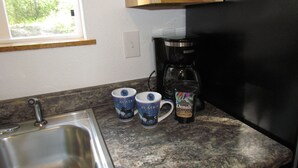 A kitchen with a stainless steel sink, a coffee maker, and two mugs on the counter. - Peaceful Talkeetna Getaway 4 (Talkeetna)