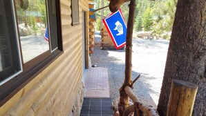 Une cabane en bois avec un mur fait de rondins, un sol à carreaux et une rambarde en bois rustique.