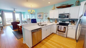 A modern kitchen with white cabinets, stainless steel appliances, and a wooden floor. - Ocean Views & Central location~ Pier Point Villas B202 (Folly Beach)