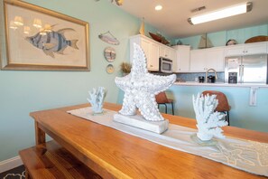 A dining area with a wooden table, a large white sculpture, and a framed fish painting.