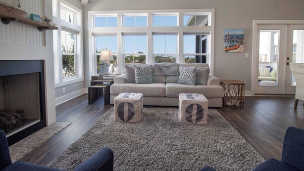 A spacious living room with a large window, a fireplace, and a sofa with patterned cushions. - Across from the beach luxury~ Folly Beach Stay (Folly Beach)