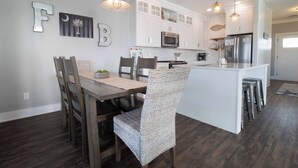 A modern kitchen with white cabinetry, stainless steel appliances, and a central island with bar stools. - Across from the beach luxury~ Folly Beach Stay (Folly Beach)