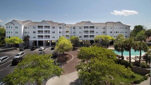 A multi-story hotel with a swimming pool, parking lot, and landscaped areas. - The Perfect 30 Day Escape! ~ My Getaway Home (Charleston)