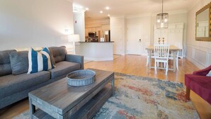 A modern living room with a gray sofa, a wooden coffee table, and a dining area with a white table and chairs. - The Perfect 30 Day Escape! ~ My Getaway Home (Charleston)