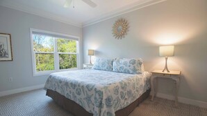 A bedroom with a large bed, two bedside lamps, a window, and a decorative wall piece. - The Perfect 30 Day Escape! ~ My Getaway Home (Charleston)