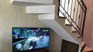Een flatscreen televisie op een houten standaard in een kamer met een trap en een structuurwand.