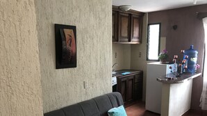 Een knus woongedeelte met een bank, een kitchenette en een kleine eethoek.