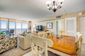 Relax in this stylish living room with a large dining table, comfortable sofa, and ocean views.