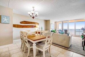 Cozy living area with a dining table for four, a chandelier, and a large window offering a view of the outdoors.