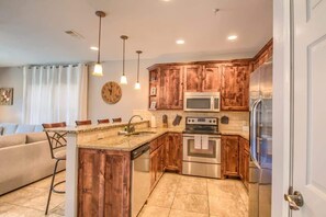 A kitchen with wooden cabinets, stainless steel appliances, and pendant lighting.