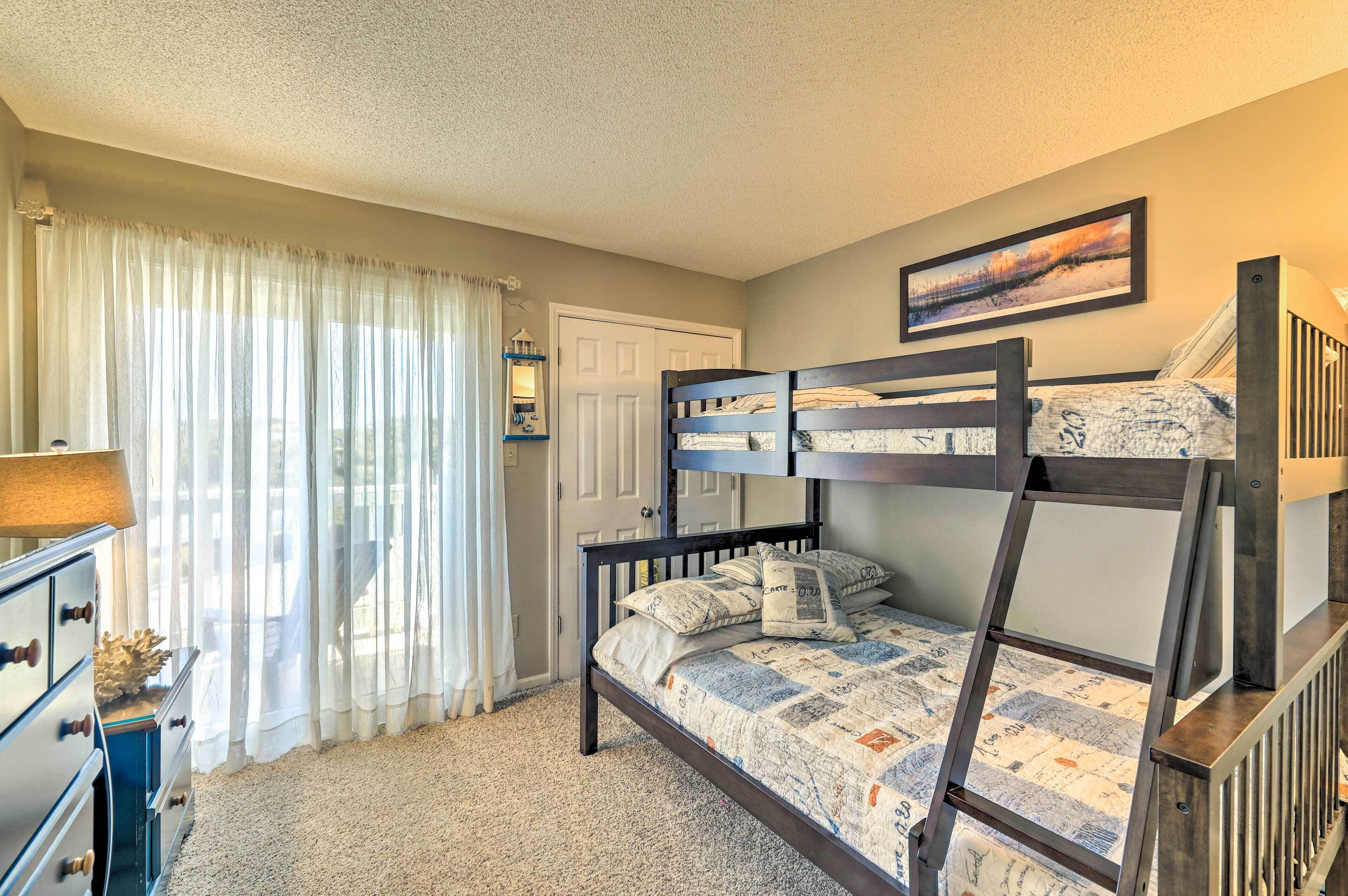 Habitación con literas, una lámpara, un aparador y una puerta.