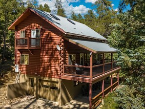 A log cabin with a balcony, a garage, and a covered porch. - Family Fun Log Cabin in the Pines - Game Room + Firepit  + Slide (Prescott)