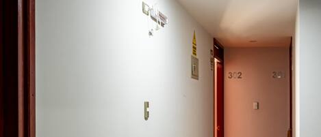 Un pasillo con paredes blancas, suelo de madera y una puerta marcada con los números 302 y 301.