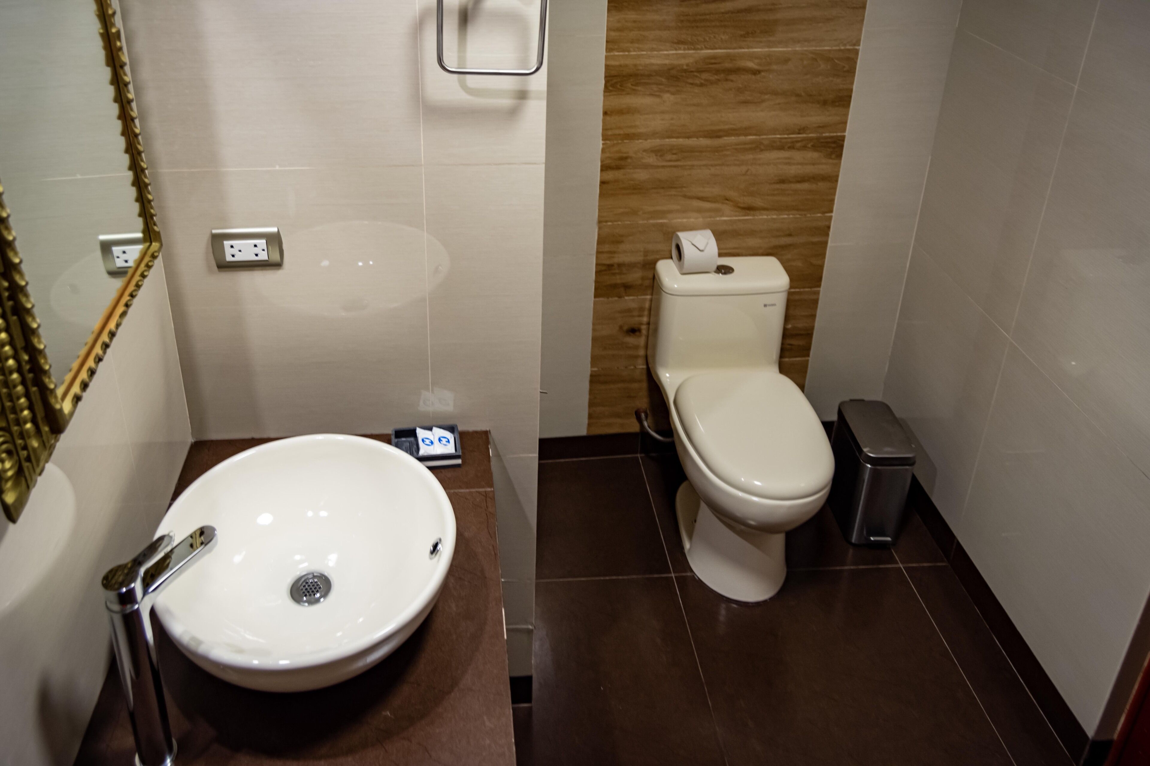 Une salle de bain avec un lavabo blanc, des toilettes et une poubelle.
