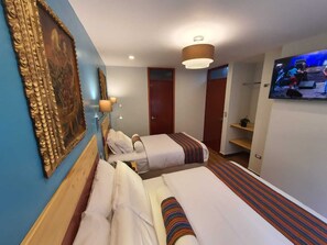 A hotel room with two beds, a television, a painting, and a lamp. - HOTEL LUZ GARDEN (Machu Picchu)
