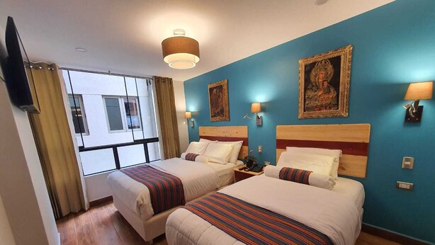 Una habitación de hotel con dos camas, un ventanal grande y obras de arte en las paredes.