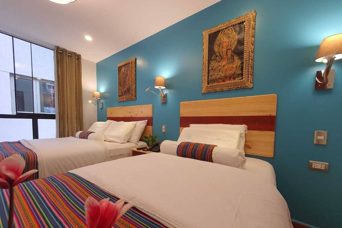 A hotel room with two beds, a large window, and wall-mounted artwork.