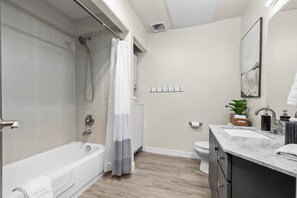 Un baño moderno con bañera, ducha, inodoro y zona de lavamanos.