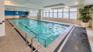 An indoor swimming pool with clear water, tiled walls, and a metal ladder. - Chic CBD Studio-Aircon-Wifi -Heated Pool (Auckland)