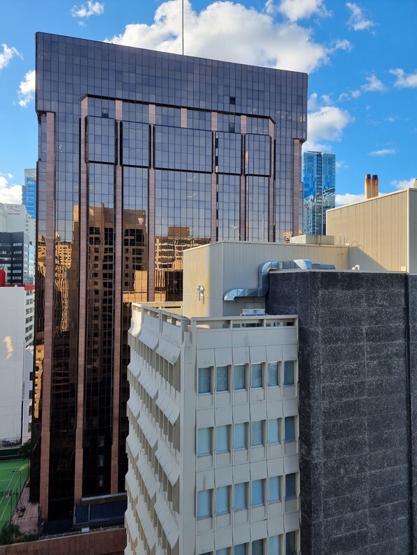 A modern building with a reflective glass facade, a prominent vertical structure, and a rooftop with a satellite dish.